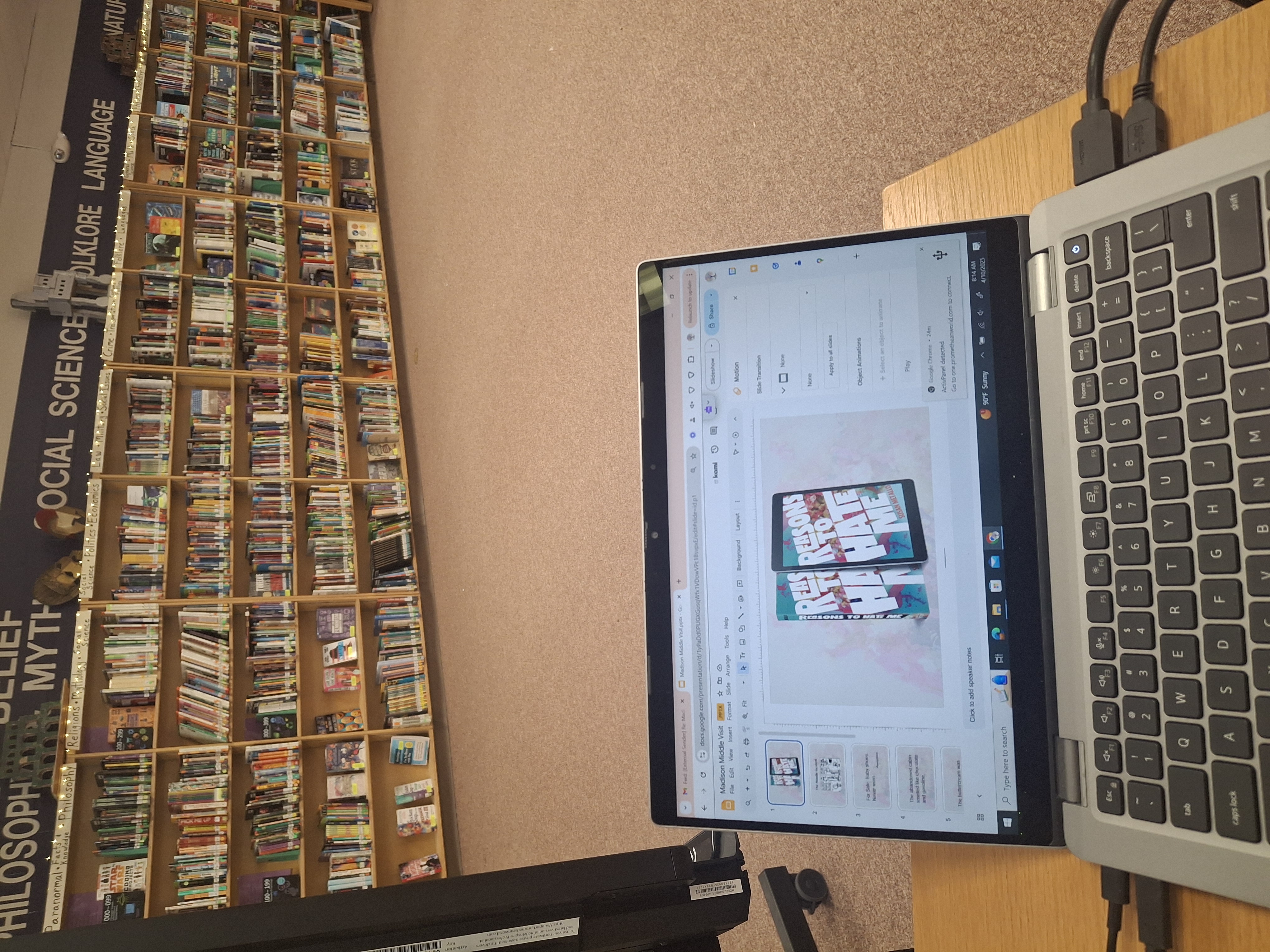 A laptop is open to powerpoint with an image of Reasons to Hate Me in a school library